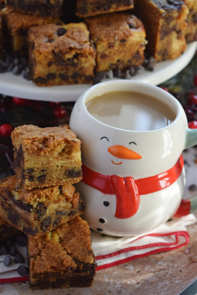 A stack of cookie bars with a snowman mug.