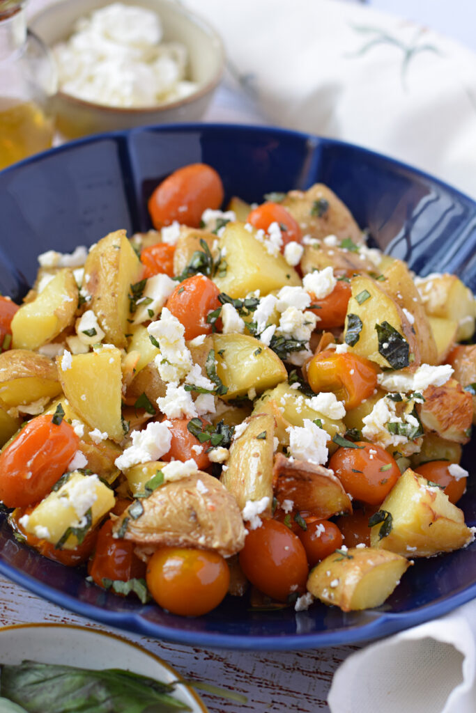 close up of potato and feta salad in a blue bowl.
