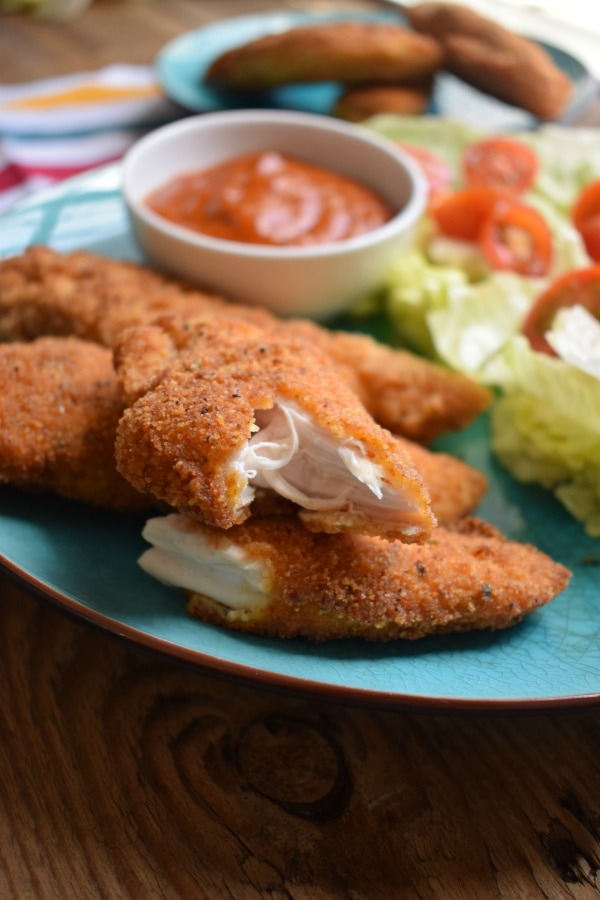chicken strip on a plate with sauce and salad