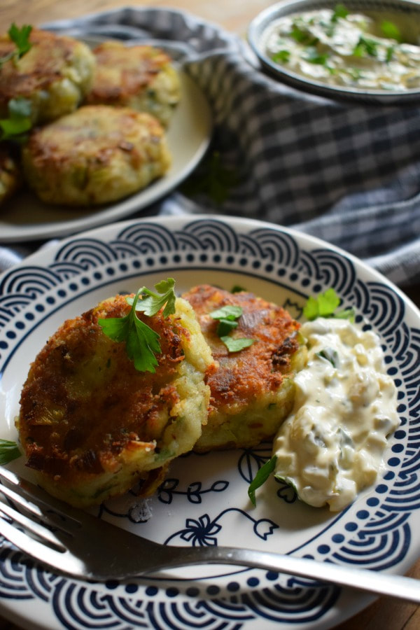 cod cakes on a plate with tartar sauce and some in the background