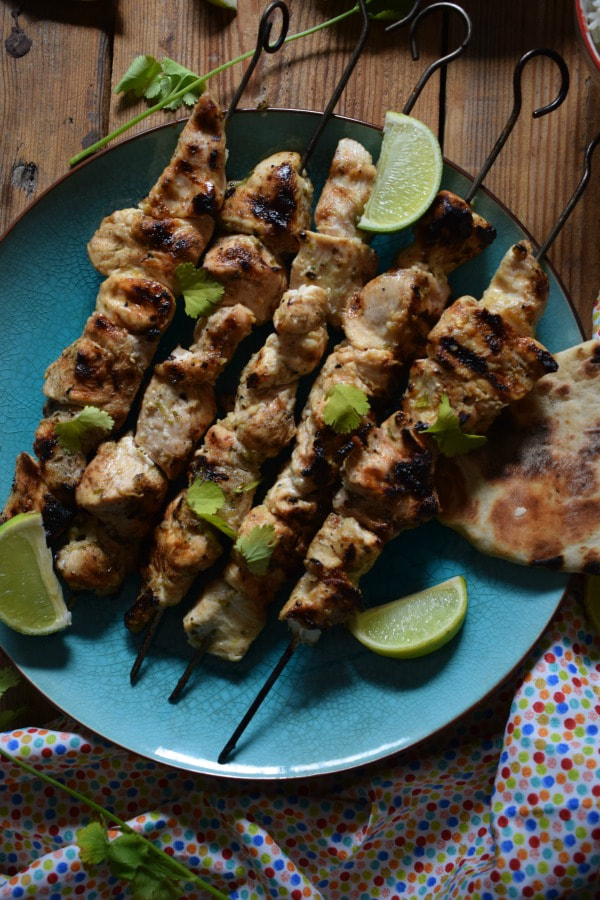 Ginger & Lime Chicken Kebabs on a blue plate with lime pieces and a tea towel