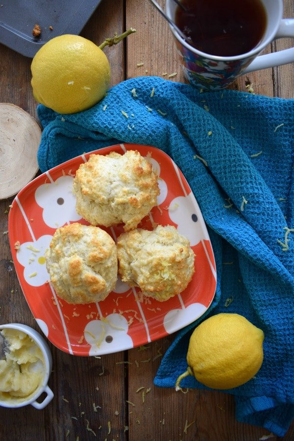 Table setting of lemon scones with butter, lemons and a cup of tea