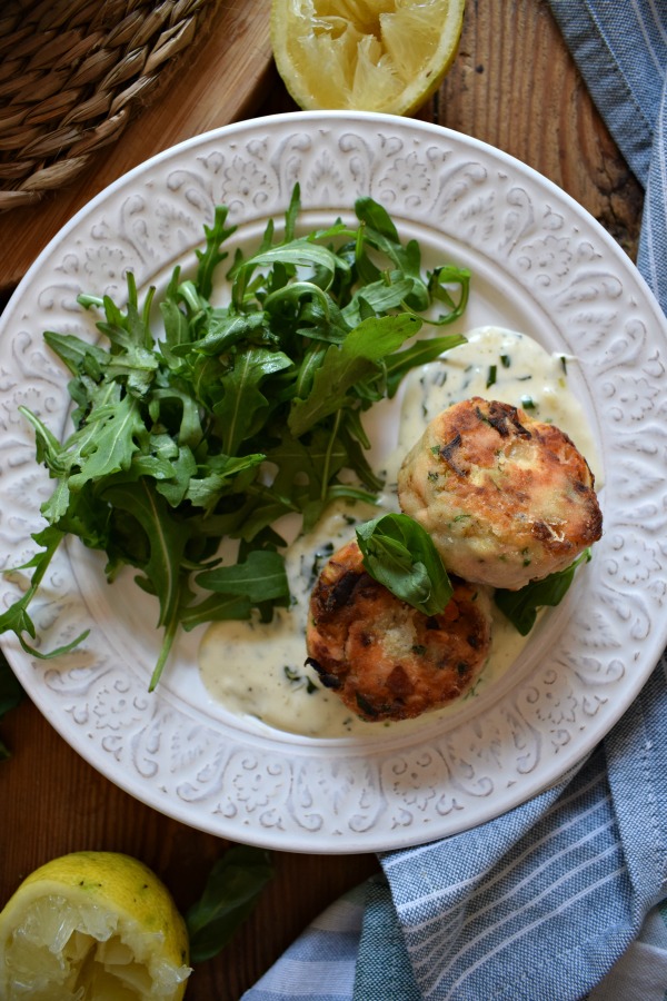 Salmon & Leek Cakes on a plate with sauce and salad leaves