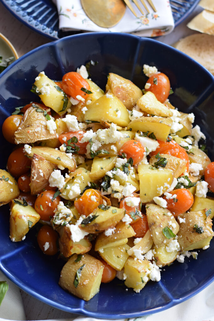 Close up of a potato and feta salad in a blue bowl.