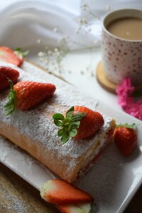 a strawberry swiss roll cake on a serving platter