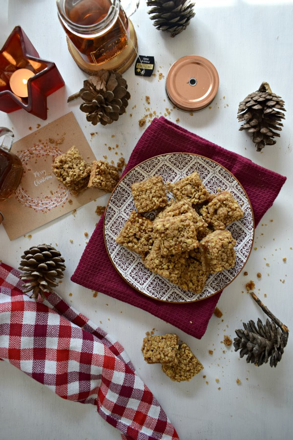 crumble bars on a white table with Christmas decor and a mug of tea