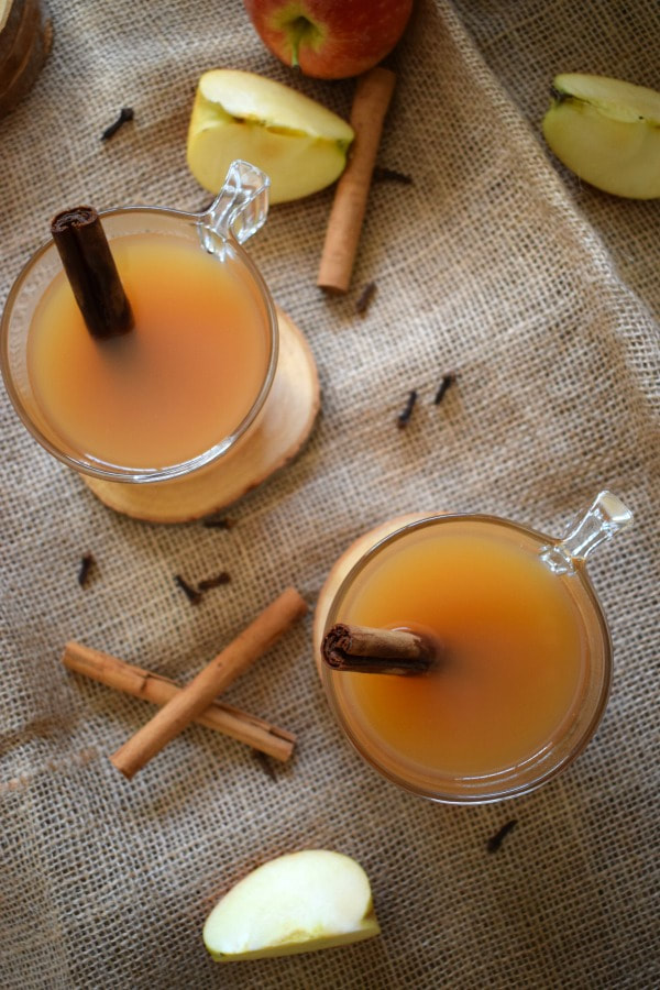 overhead view of apple cider with apple pieces and cinnamon sticks