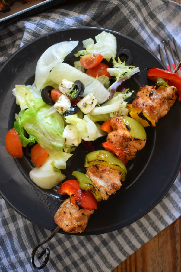 Cajun Chicken Kebabs on a black plate with a salad