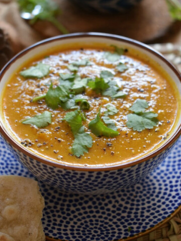Close up of carrot and coriander soup in a bowl.