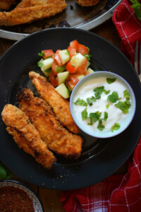 Chicken strips on a plate with a dip.