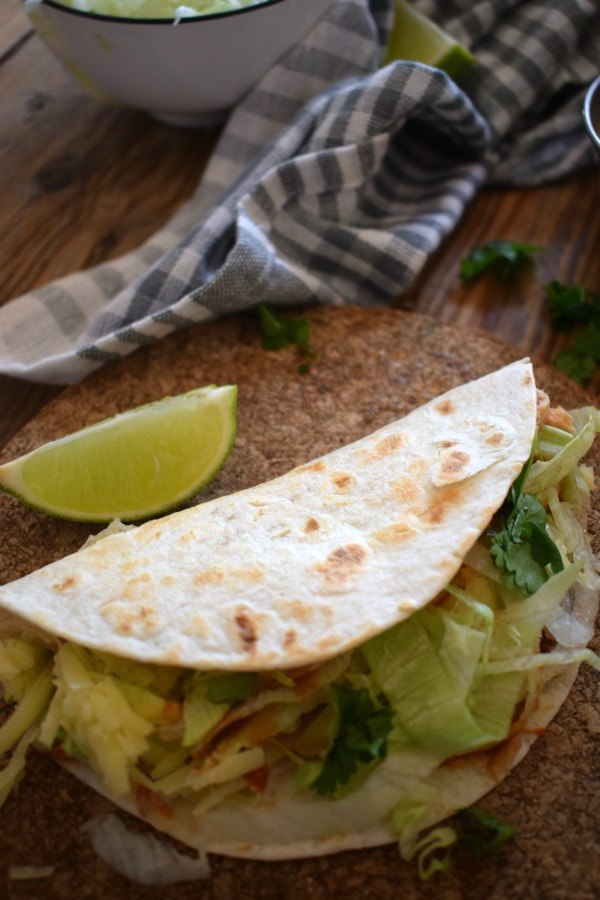 a close up of a slow cooked chickne taco with a lime