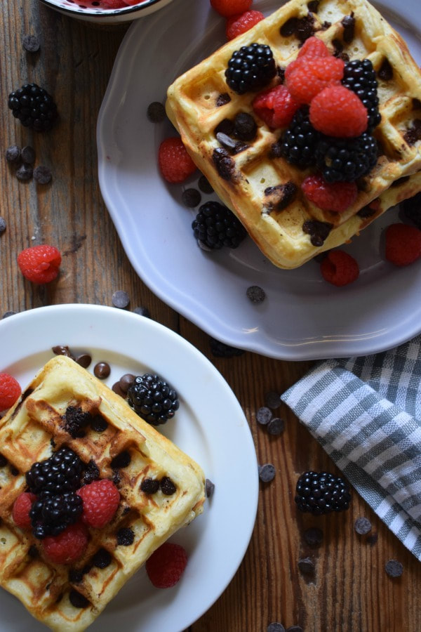 Chocolate chip waffles on a wooden table with berries.