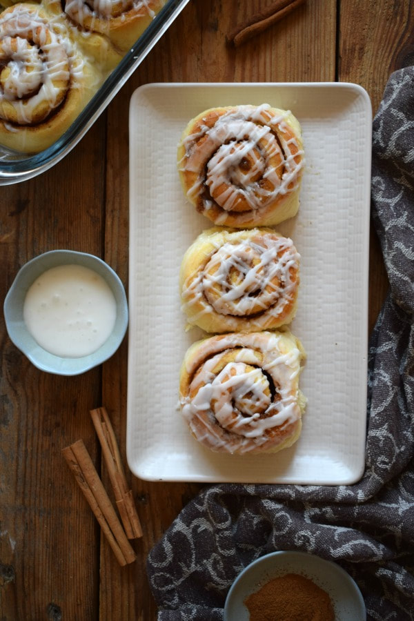 over head view of cinnamon rolls, cinnamon sticks and glaze