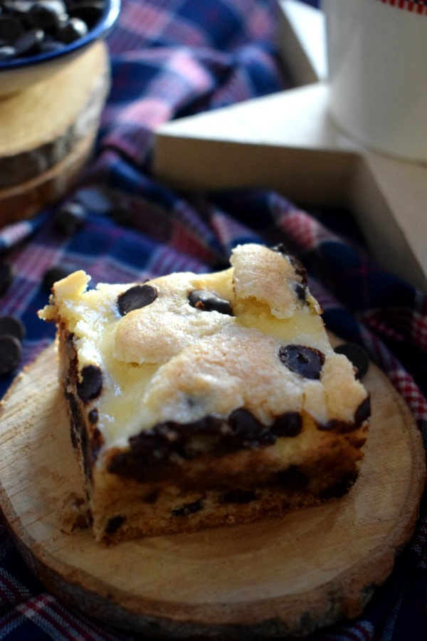 Close up of Cream Cheese Chocolate Chip Squares on a coaster with a checked tea towel