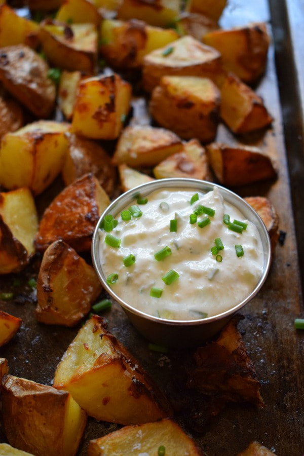 close up of the crispy garlic potatoes with a creamy chive dip on a tray