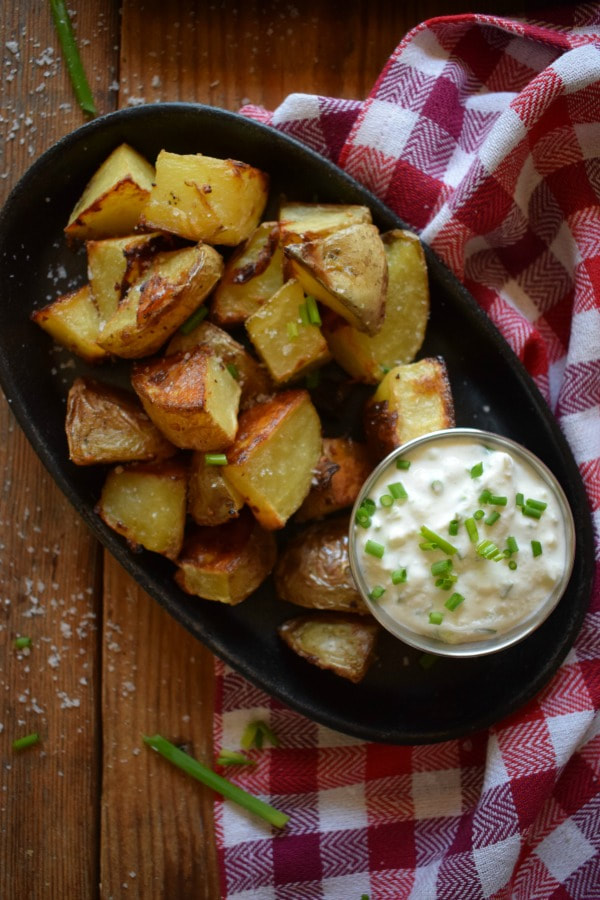 Creamy Garlic Potatoes with a Creamy Chive Dip on a black plate with a tea towel