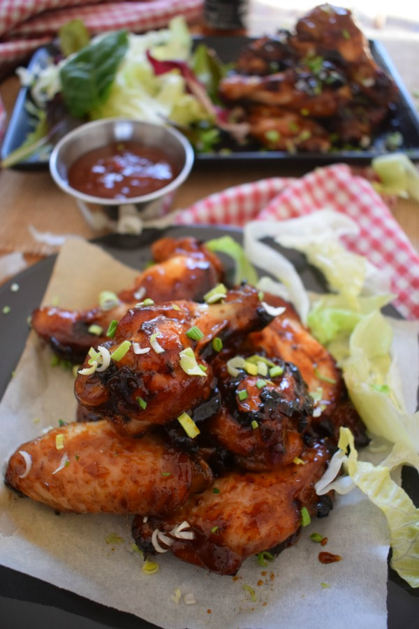 Close up of the sticky honey garlic wings with dipping sauce and lettuce leaves