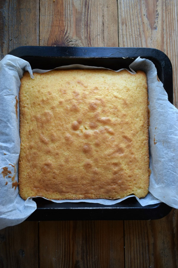 A vanilla cake baked in a square baking pan.