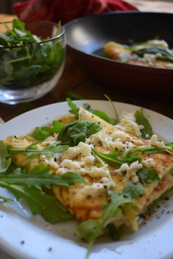 Mozzarella and basil omelette on a serving plate with fresh arugula in the background