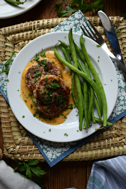pork medallions on a plate with a dijon mustard sauce and green beans