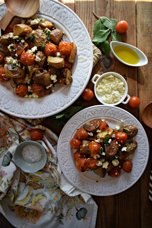 Overhead table view of the Roasted Potato and Cherry Tomato Salad with napkins, feta and olive oil