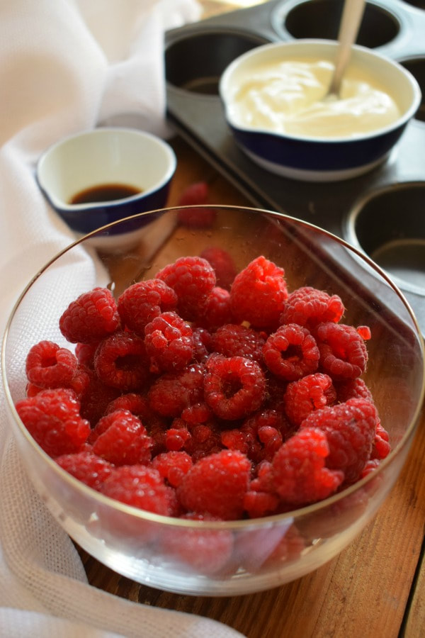 close up of raspberries in a bowl with ingredients in the background