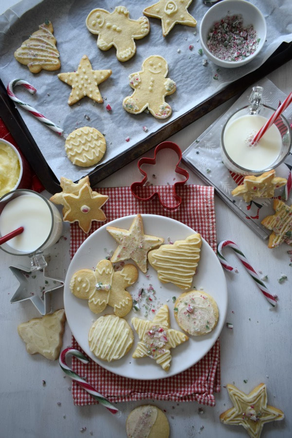 butter cream topped sugar cookies with decorations, milk, candy canes and cookie cutters