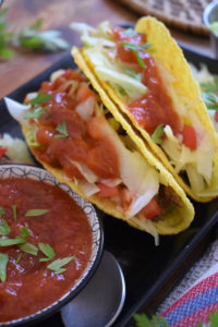 Beef tacos on a black plate.