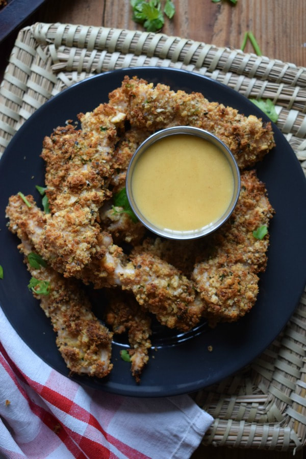 parmesan crusted turkey tenders on a plate with a dipping sauce and a napkin