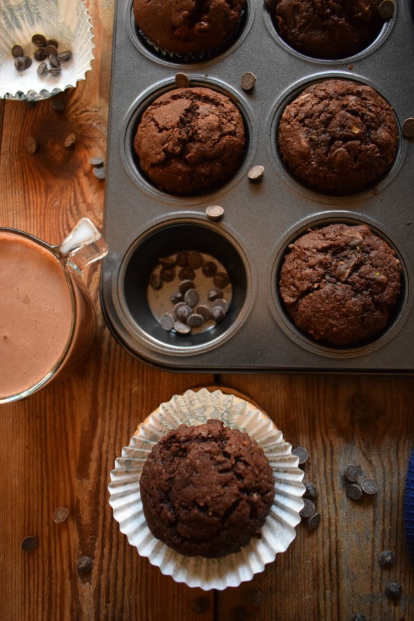 Overhead view of the Chocolate Zucchini Muffins, a glass of chocolate milk and some chocolate chips