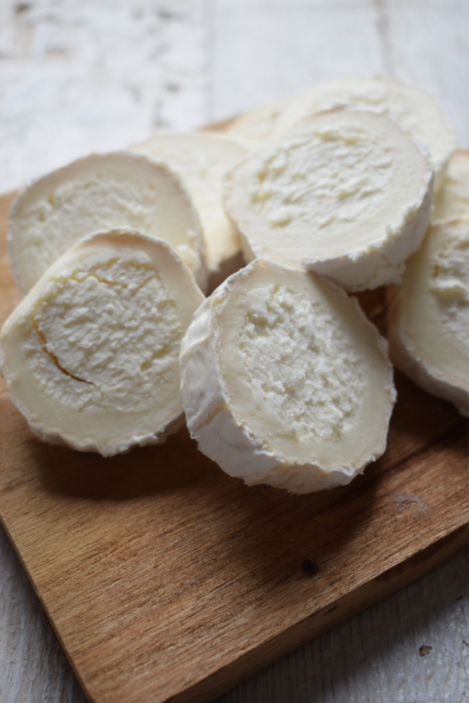 Goat cheese rounds on a wooden board.