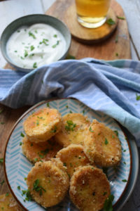 Fried goat cheese appetizer on a plate with dipping sauce and a beer.