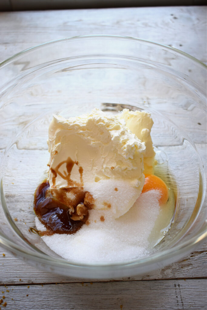 Making cheesecake filling in a glass bowl.