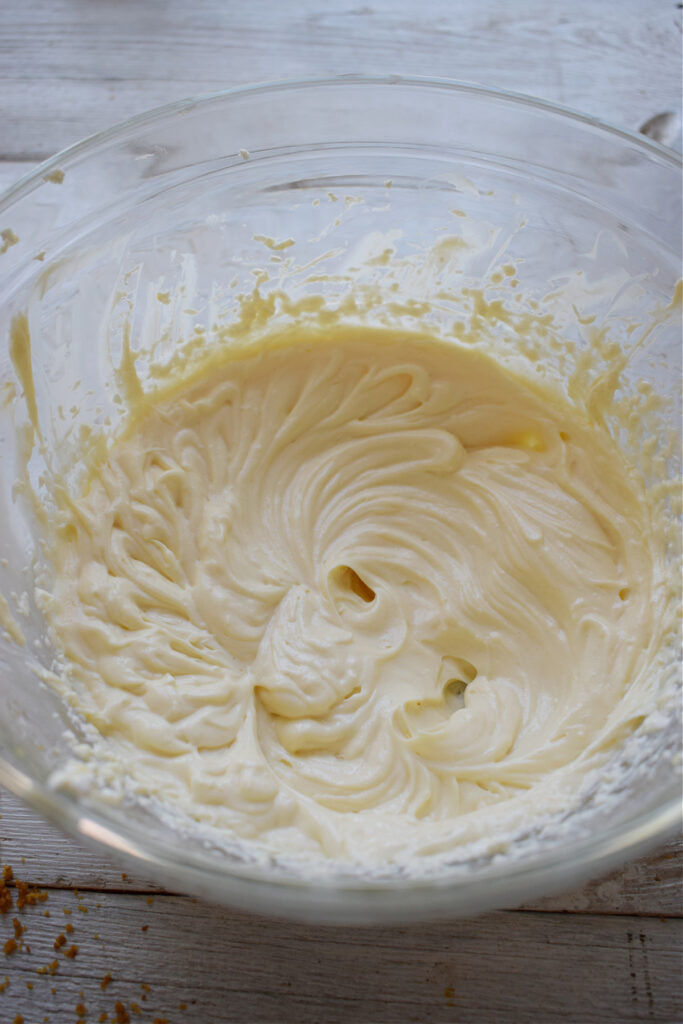 Making cream cheese filling in a glass bowl.