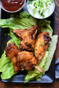 marinaded wings on a tray with dipping sauces