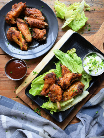 Oven baked chicken wings on a plate and a serving tray.