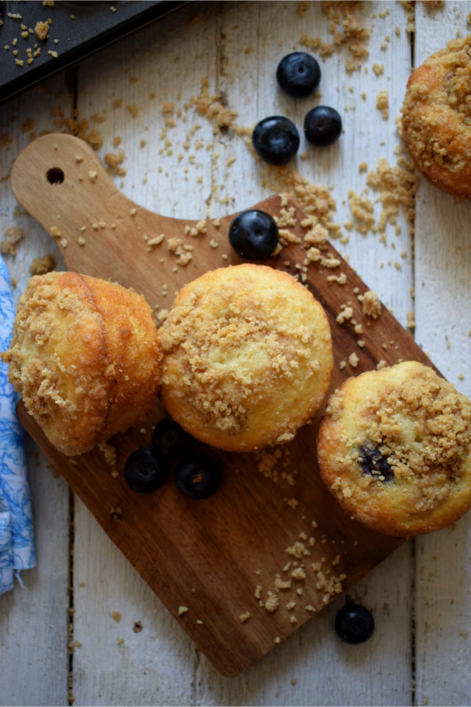 Overhead view of blueberry strudel muffins on a wooden board with a blue napkin