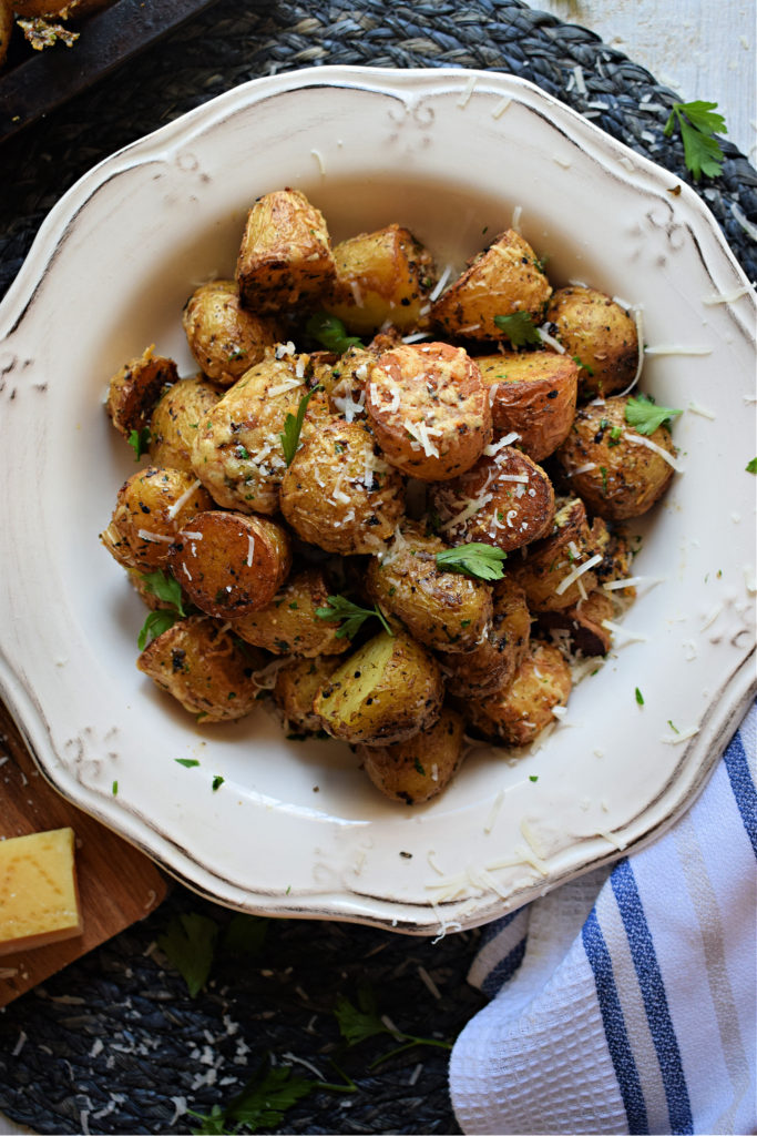 Crispy potatoes in a white china bowl with a white and blue tea towel