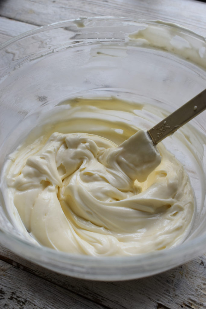 cream cheese frosting in a glass bowl with a spatula