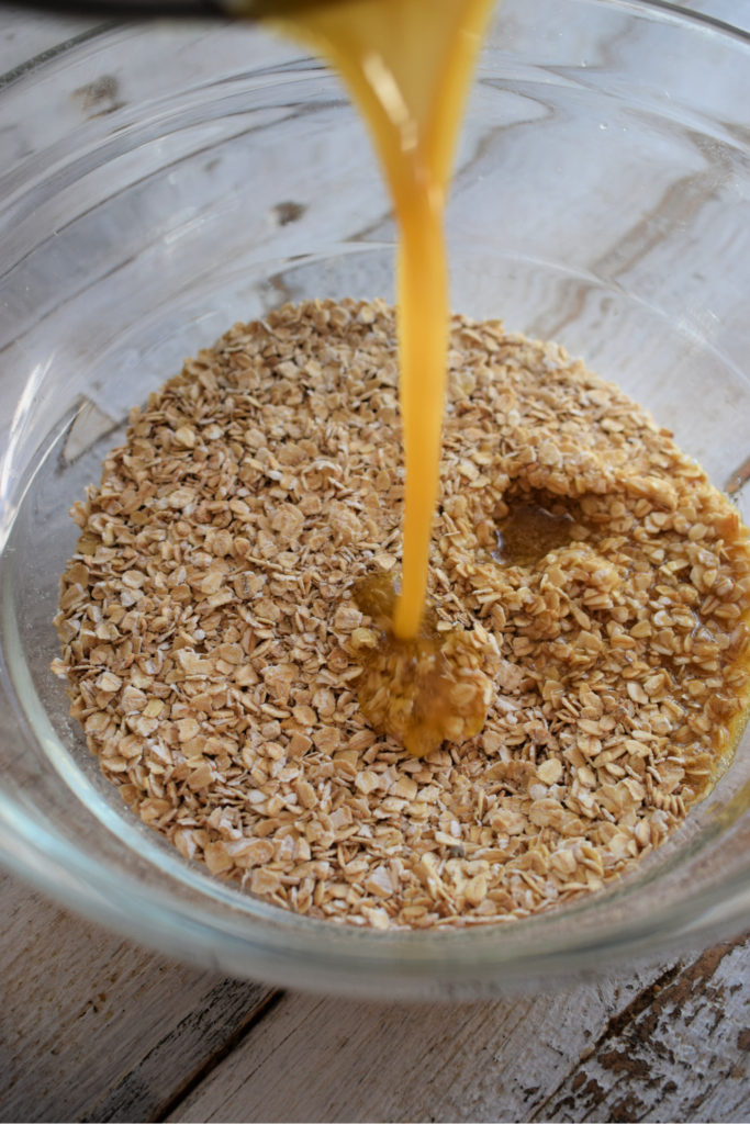 Pouring melted butter into oats.