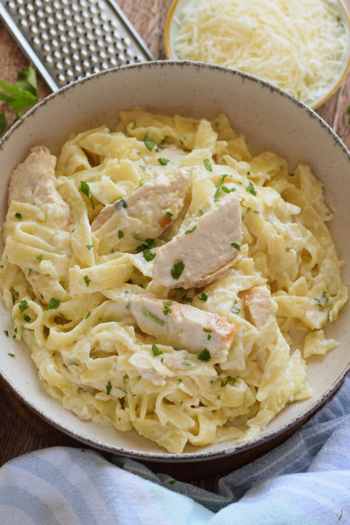 Chicken alfredo in a whtie serving bowl.