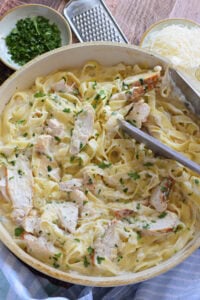 Chicken alfredo in a white skillet.