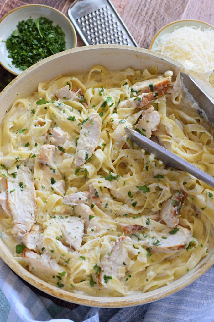 Chicken alfredo in a white skillet.