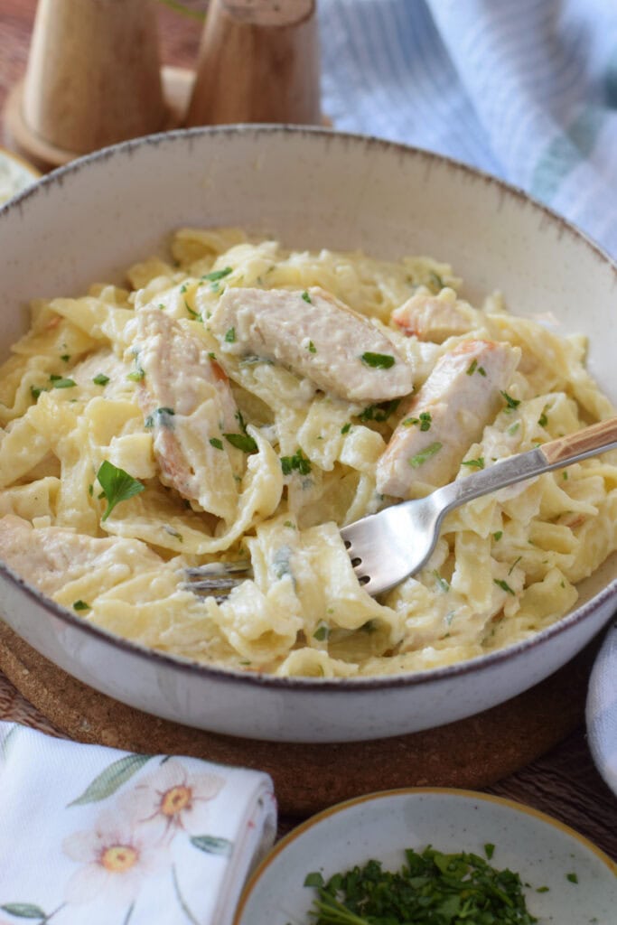Close up of creamy chicken alfredo in a serving bowl.