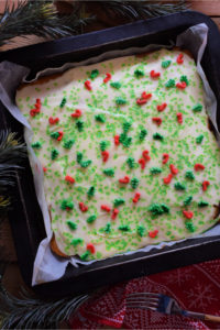 Vanilla cake squares in a baking tin with Christmas sprinkles.
