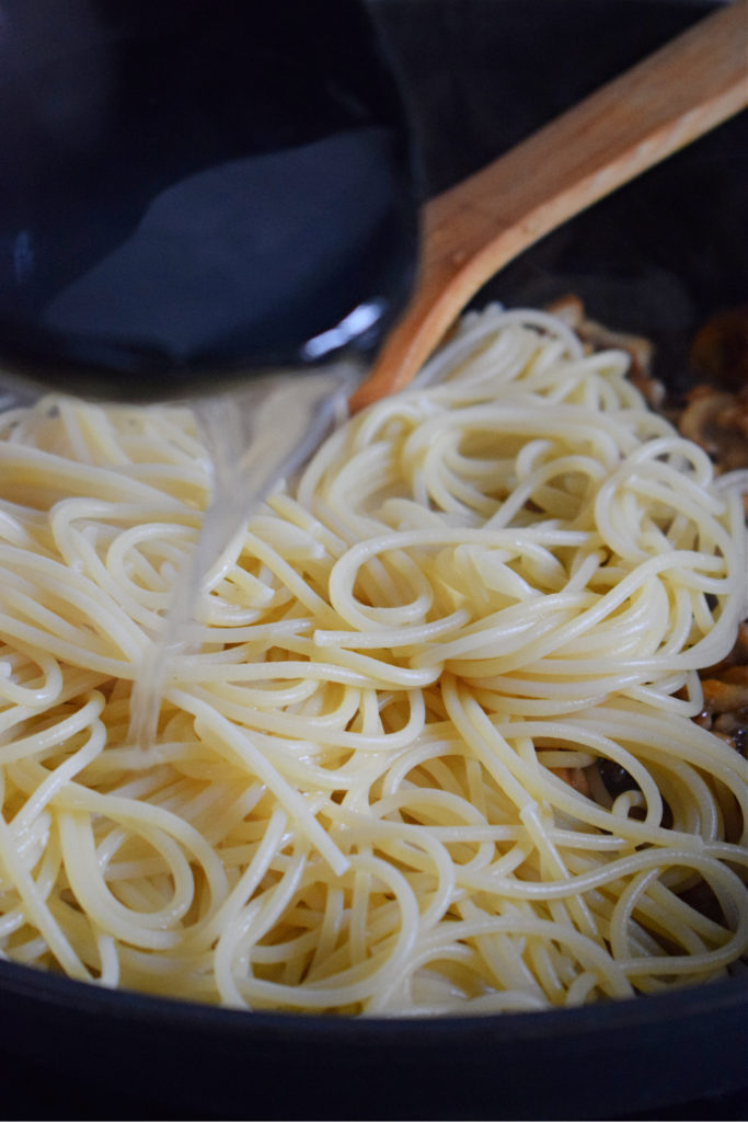 adding pasta water to spaghetti