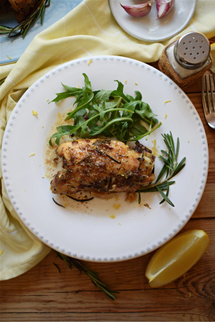 lemon and rosemary chicken on a plate with arugula
