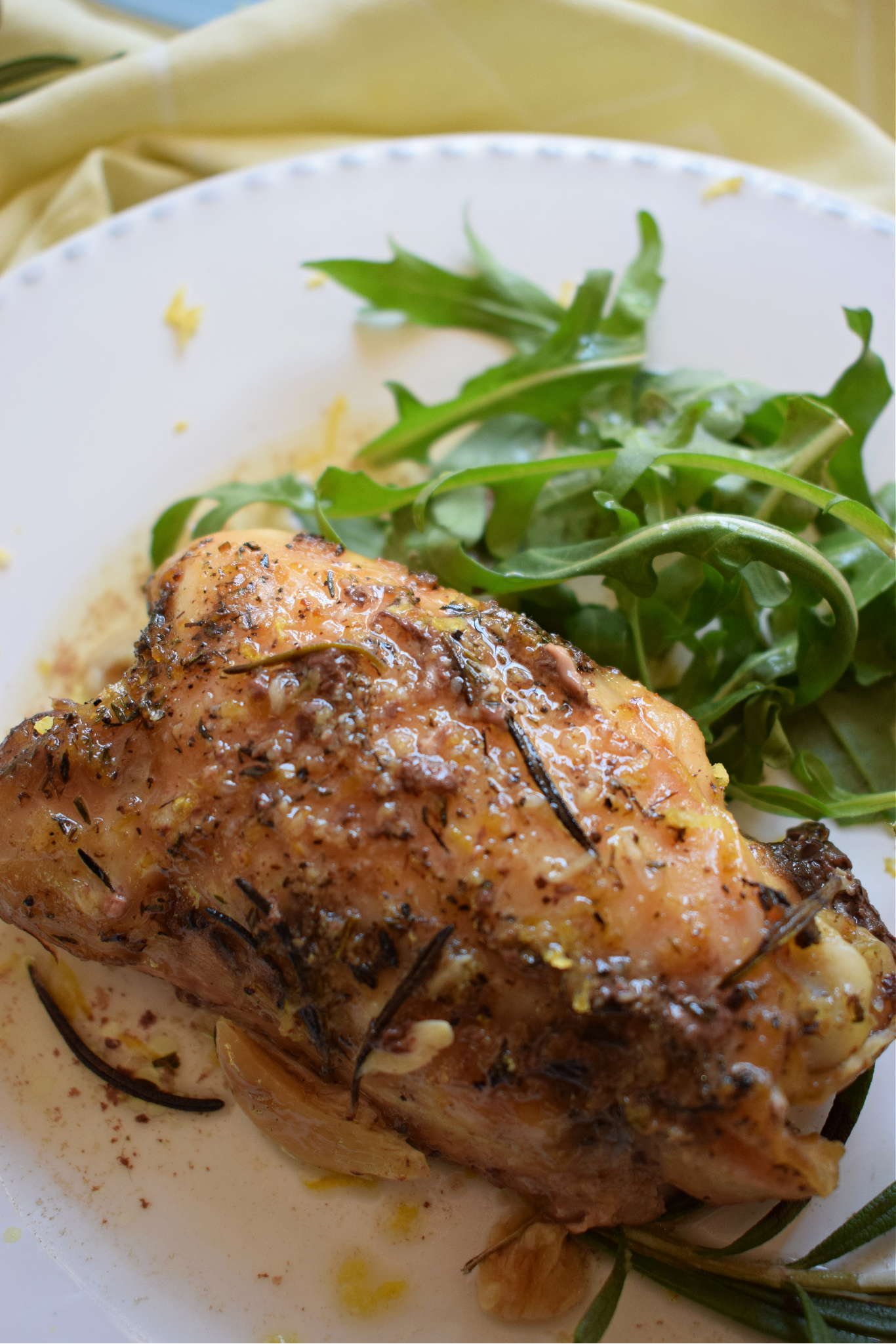 Slow cooker lemon and rosemary chicken on a plate with arugula