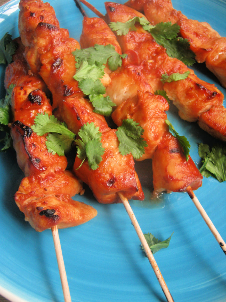 weet and spicy chicken kebabs on a blue plate