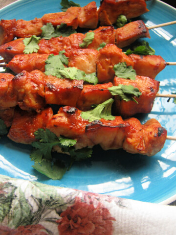 Sweet and Spicy Chicken Kebabs on a blue plate with a floral napkin
